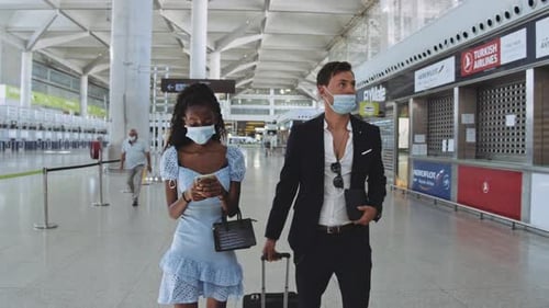 Man and Woman Travelers By the Terminal Gate Entrance in Surgical Masks On