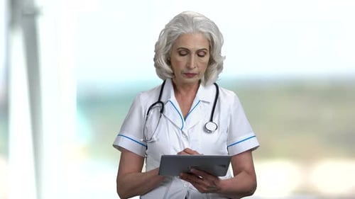 Senior Woman Doctor Using Tablet Device