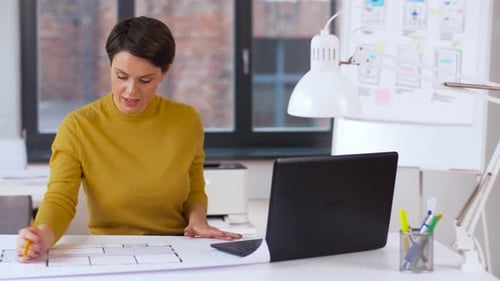 Architekt mit Blueprint und Laptop im Büro 1