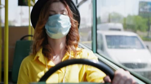 Woman Wearing Mask Rides Bus Holding Steering Wheel