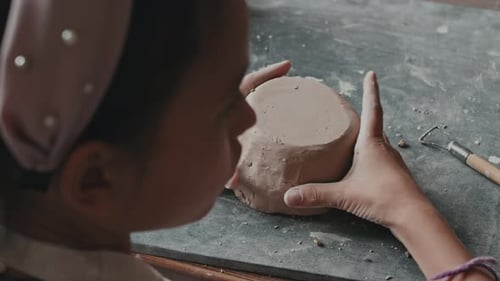 Girl Creating Clay Pot at Table Indoors