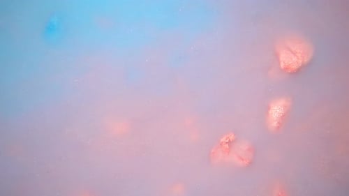 Glittering Pieces Floating in Pink and Blue Liquid