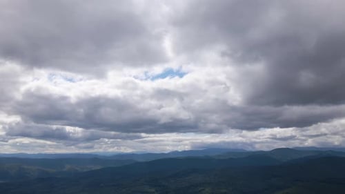 Aerial View From High Altitude of Distant Mountain Hills Covered with Puffy Cumulus Clouds Forming
