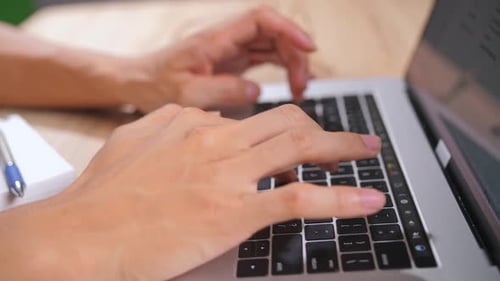 Hands Typing on Laptop at Wooden Desk