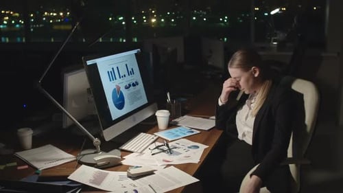 Tired Businesswoman Analyzing Stats at Night