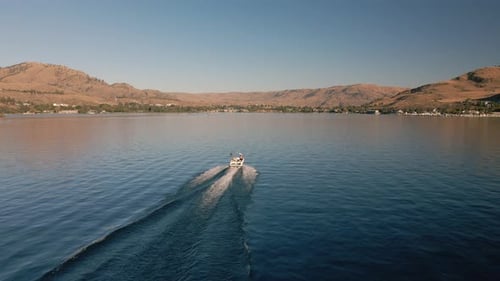 Boat Cruising Calm Lake Water In Scenic Environment With Drone Following