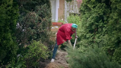 Young African American Man Digging Ground in Garden with Shovel