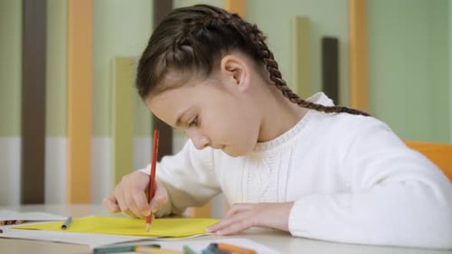 Nahaufnahme Seitenansicht eines hübschen konzentrierten Mädchengemäldes mit Bleistift am Schreibtisch