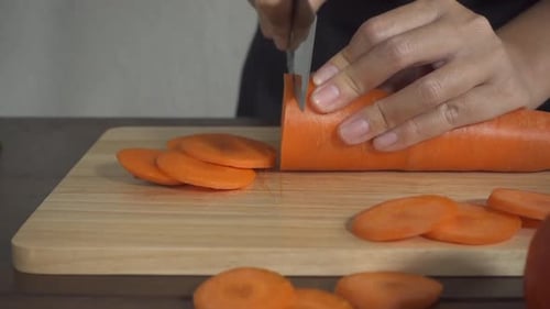 Hands Slicing Fresh Carrot on Cutting Board