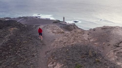 Jogger läuft auf dem Weg zum Leuchtturm der Insel Ponta Dos Capelinhos Faial