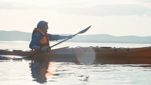 Man Paddling Kayak on Calm Lake During Day