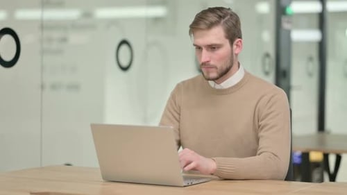 Man Working on Laptop in Modern Office