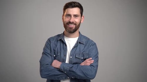 Portrait of happy satisfied handsome young man standing with crossed arms and looking at camera