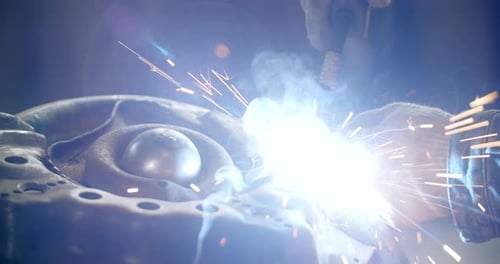 Schweißer schweißt dekoratives Metalldetail mit Schweißpunkten Schweißen mit Rauch und Funken in Zeitlupe