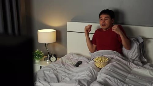 Man Watching Scary Movie at Night in Bedroom