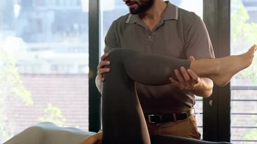 Physical Therapist Manipulating Woman's Leg in Office