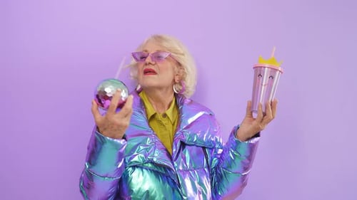 Cheerful Smiling Woman of Retirement Age Posing in the Studio on an Isolated Background Holding Two