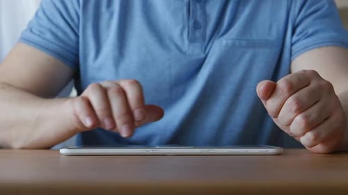 Man Using a Tablet on a Wooden Table