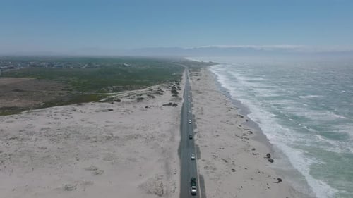 Aerial Descending Shot of Cars Driving on Road Along Ocean Coast