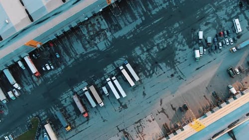 Trucks Stand in Row on Asphalt Parking Lot By Warehouse