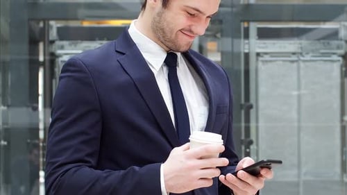Businessman With Phone and Coffee in Modern Office