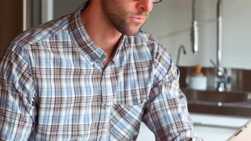 Man Using Tablet in Kitchen Wearing Glasses