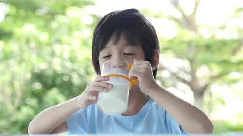 Smiling Child Drinking Milk Outside