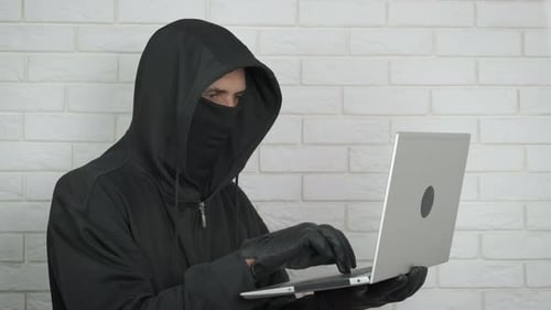 Person Typing on Laptop Wearing Hood and Gloves