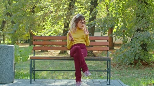 Young Happy Woman Eating Baguette in City Park