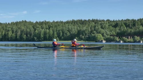 Two Women Synchronously Row on Yellow Kayak with Oars on Calm Lake, Outdoor Activities in Summer in