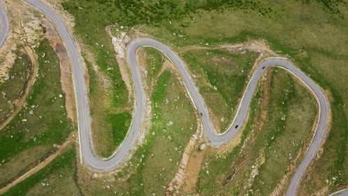 Drone footage of the grass field the winding road and driving car