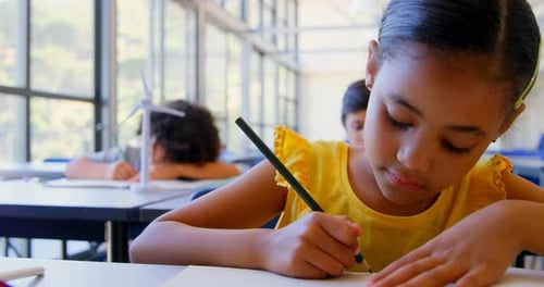 Girl Writing at Desk in School Classroom