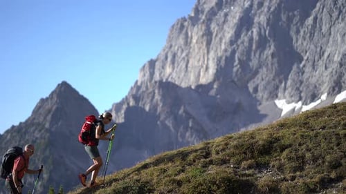 Hikers Ascend Mountain Slope on Sunny Day