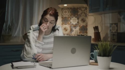 Woman In The Kitchen With Laptop. She Falls Asleep Sitting Near Laptop