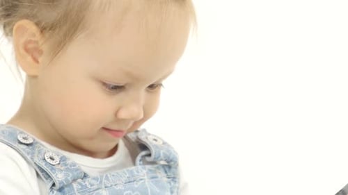 Little Child Looks Interesting Pictures on the Tablet. White Background