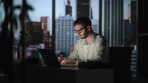 Portrait of Thoughtful Successful Businessman Working on Laptop Computer in His Big City Office at