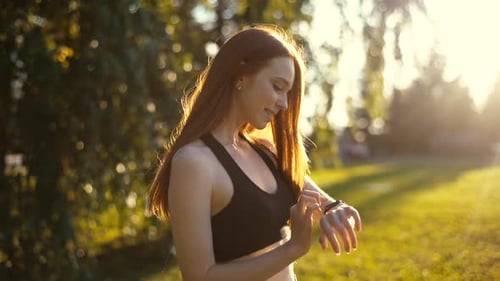 Woman Using Smartwatch in Golden Park Sunlight