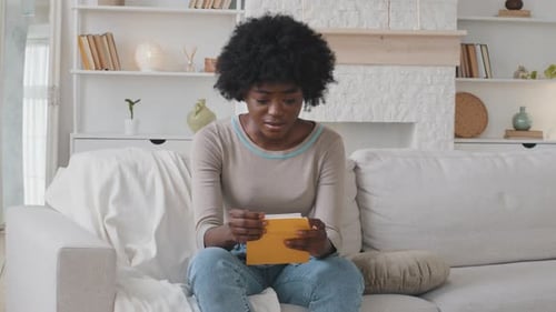 Woman Reads Letter on Couch, Sad Expression
