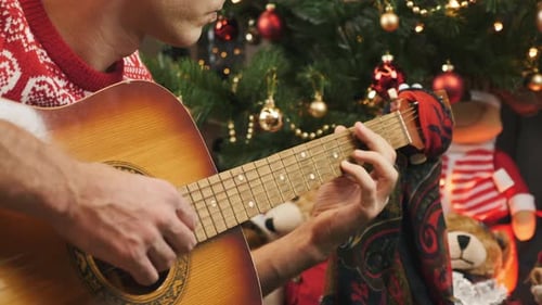Young Adult Plays Guitar at Christmas Time