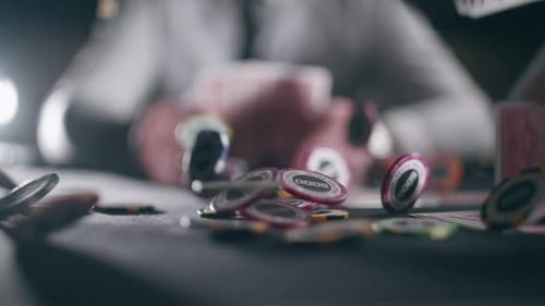 Casino Chips and Playing Cards are Falling Against the Background of a Player with Cards in Slow