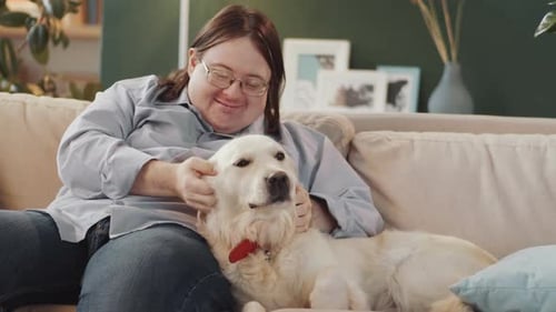 Woman Petting Golden Retriever Dog on Couch