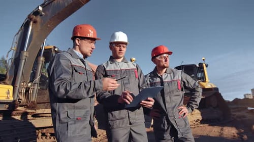 Three Men Discussing Construction Plans on Site