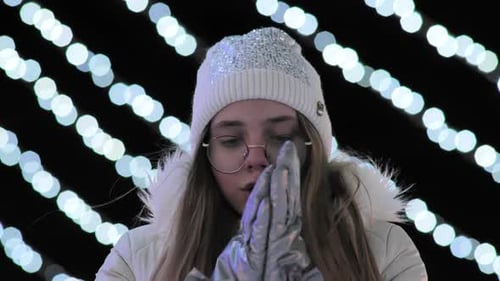 The Girl Freezes in the Evening in the City in Winter Against the Background of Gerlands
