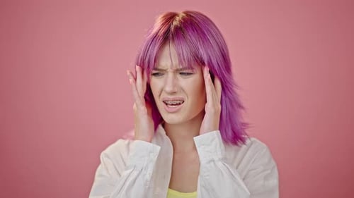 Mujer de pelo rosado se siente enferma y tiene dolor de cabeza de cerca