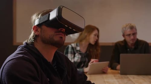 Mann trägt VR-Headset mit Kollegen, die im Kreativbüro arbeiten