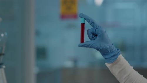 Laborant hält rote Substanz im Reagenzglas für wissenschaftliche Analysen