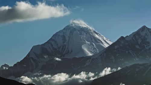 Timelapse Clouds Swirl Over a Mountain Valley a Snowy Peak in the Distance