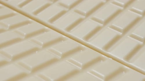 White milk chocolate blocks in a row sweet background slow tilt 4K 2160p 30fps UltraHD video - Junk