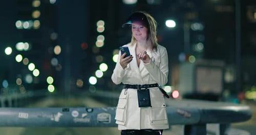 Attractive Woman Using Mobile Phone During Walk on Streets of Night Town Footage