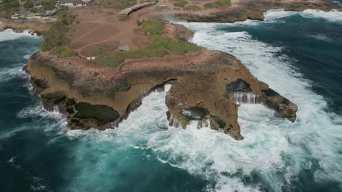 Aerial drone view of ocean waves and swell crashing into a rocky coastline
